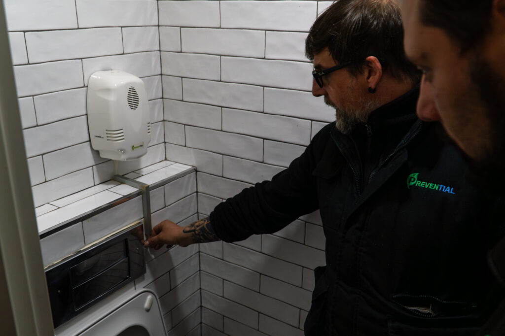 Técnico de Prevential revisando un dispensador higiénico en un aseo